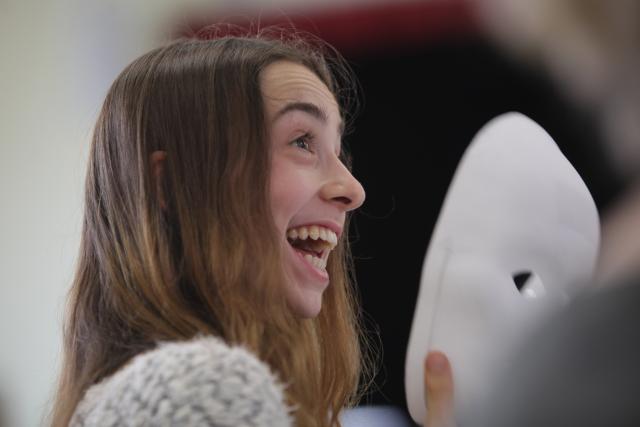 Une jeune fille retirant son masque et souriant