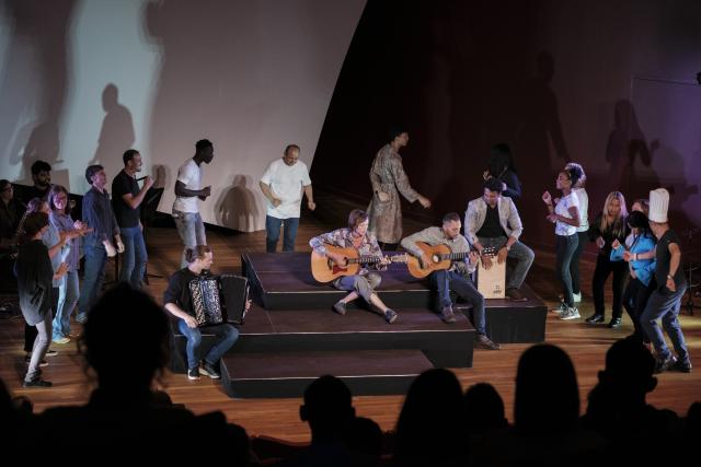 Des personnes sur scène dansant autour de trois musiciens