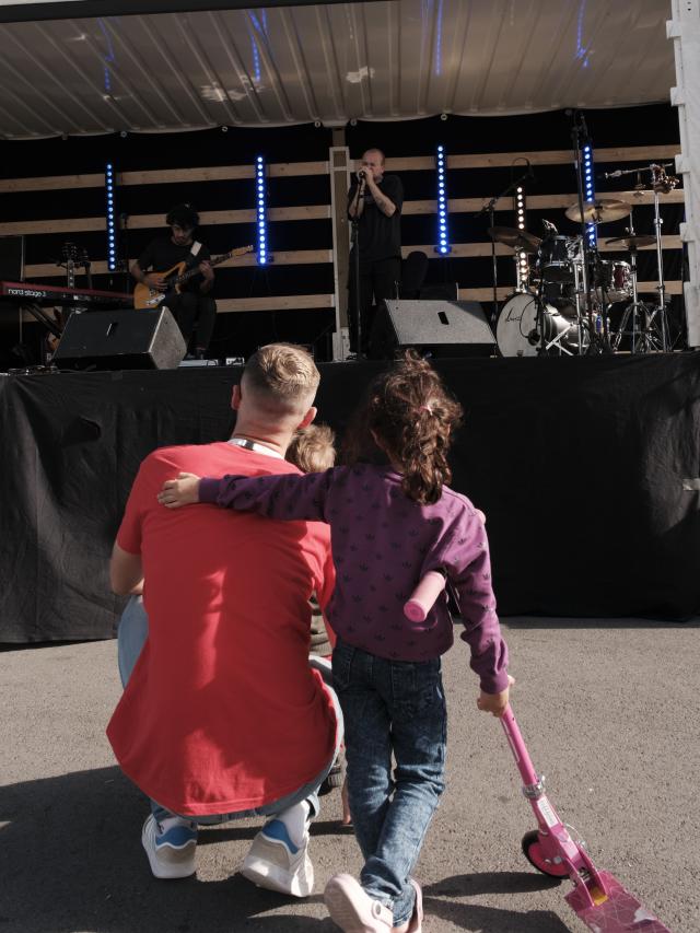 Une petite fille à côté d'un adulte regardant des artistes dans un camion converti en scène