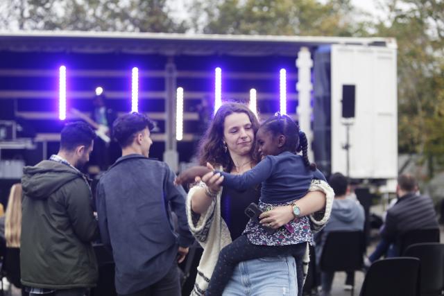 Une femme dansant avec une petite fille dans ses bras devant un camion converti en scène