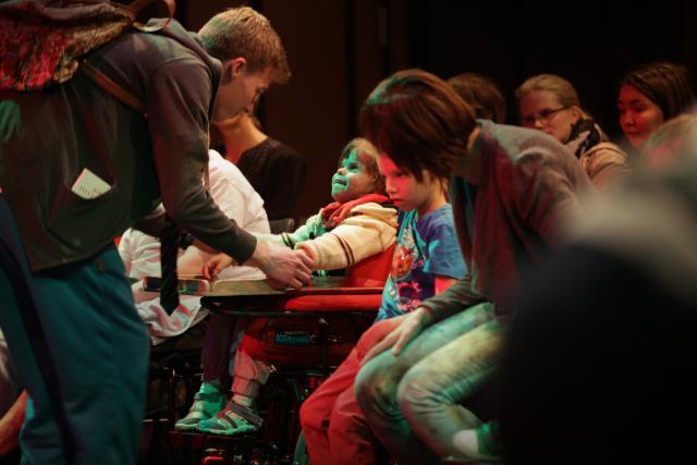 Un artiste prenant la main d'un enfant du public en fauteuil roulant