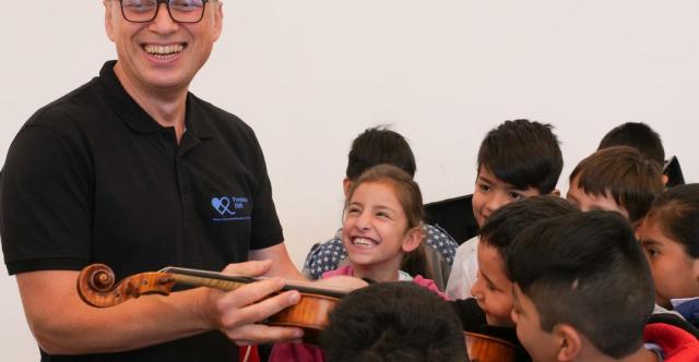 Des enfants touchant un violon en souriant
