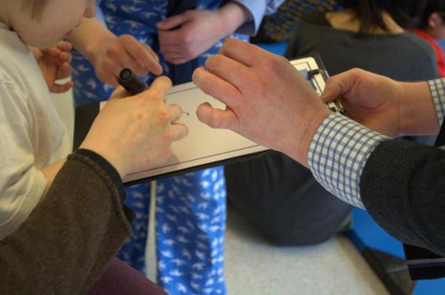 Des personnes écrivant sur une même feuille