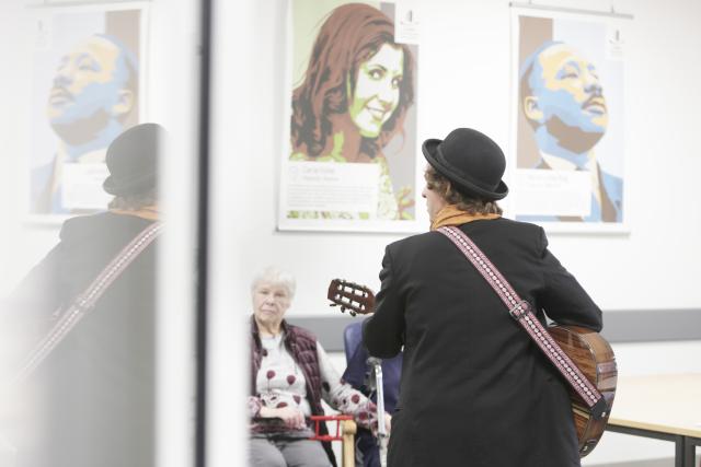 ein Gitarrist singt einer älteren Frau in einem Krankenhaus etwas vor