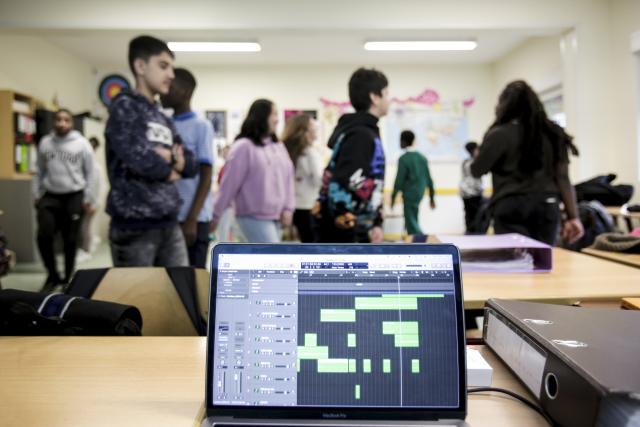 Des jeunes dansant dans une salle de classe avec un ordinateur en premier plan
