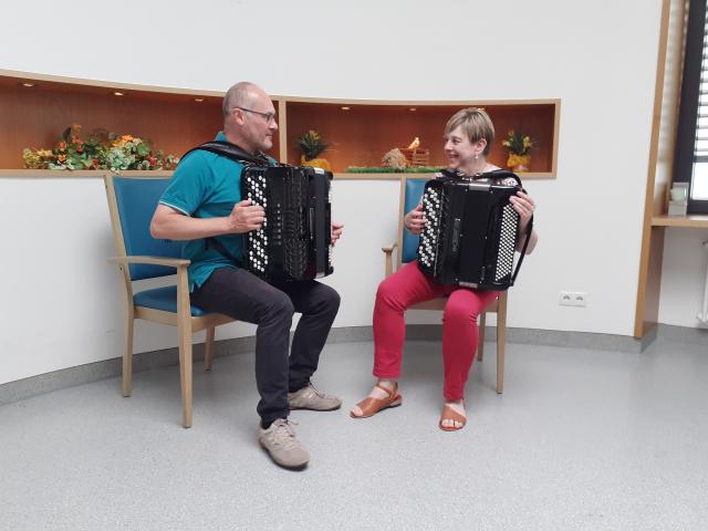 ein Mann und eine Frau, die Akkordeon spielen, sitzen und schauen sich an