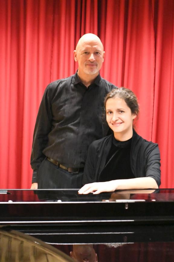Un homme et une femme devant un rideau rouge et derrière un piano