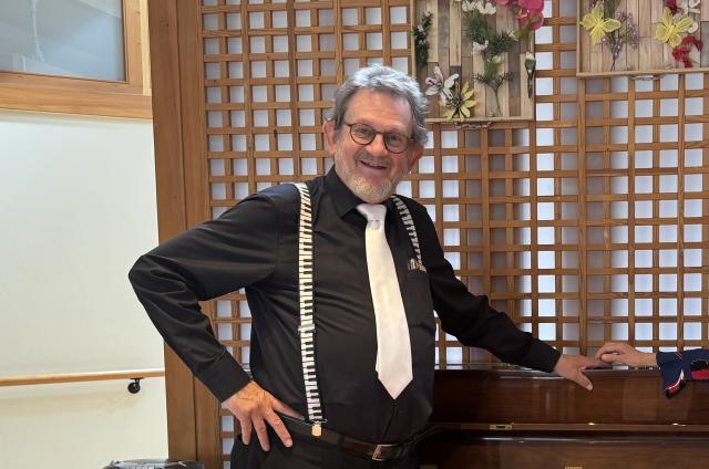 un homme devant un piano qui sourit